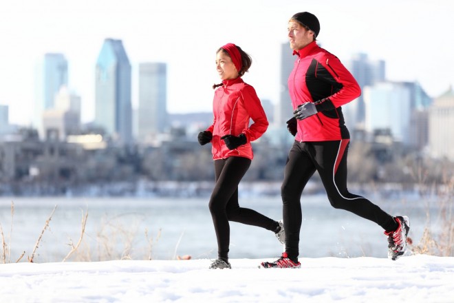 Running Pourquoi et comment courir en hiver Runners running in winter snow with city skyline background. Healthy multiracial young couple. Asian woman runner and Caucasian man running with Montreal skyline, Quebec, Canada